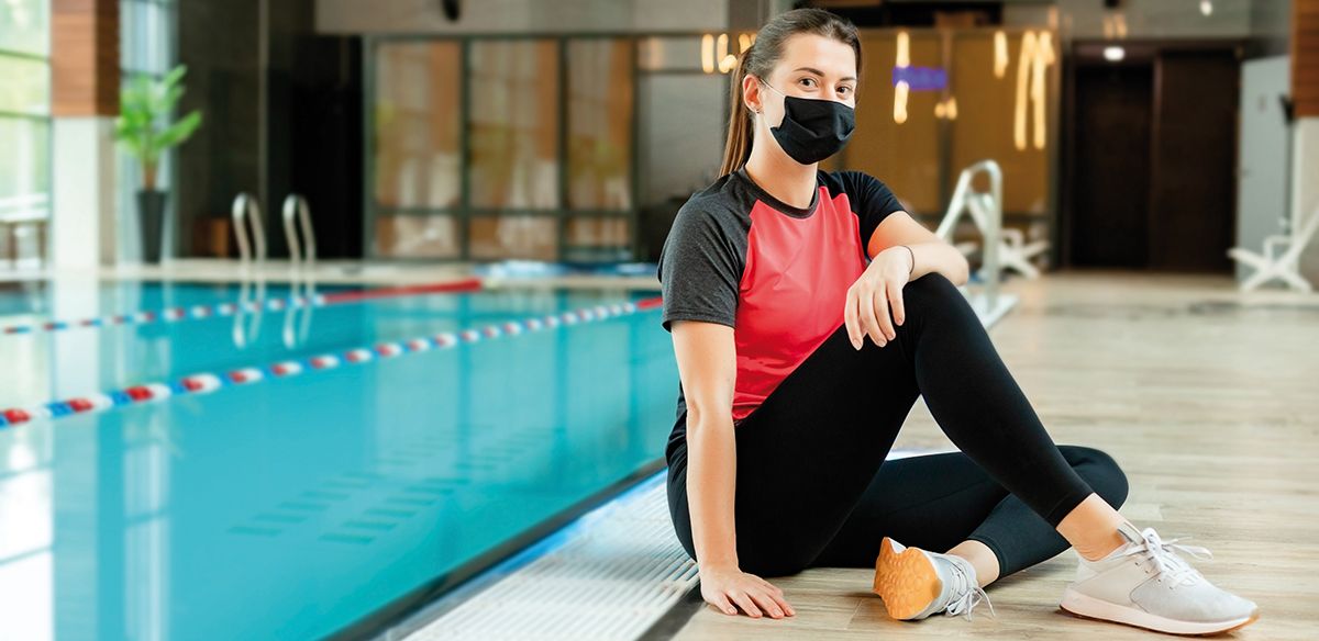 Portrait of fitness instructor with facial medical protective face mask in the swimming pool. Concept with sports coach during coronavirus. Lady is professional trainer in aqua fitness